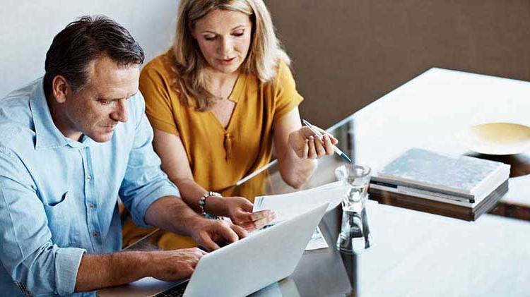 Woman and man with papers and a laptop discussing their retirement.